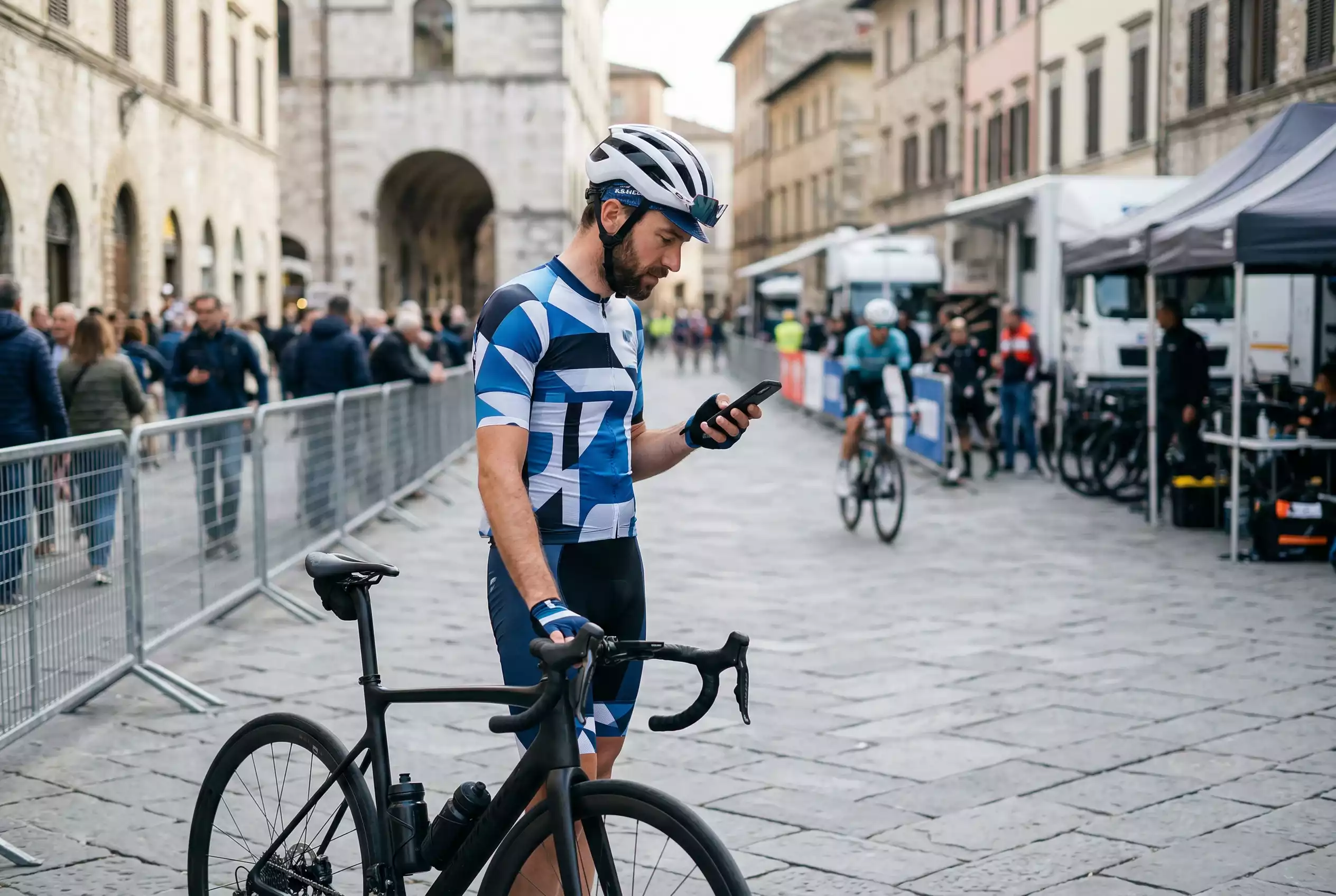 Ciclista su strada con smartphone in mano prima di una gara di ciclismo professionistico