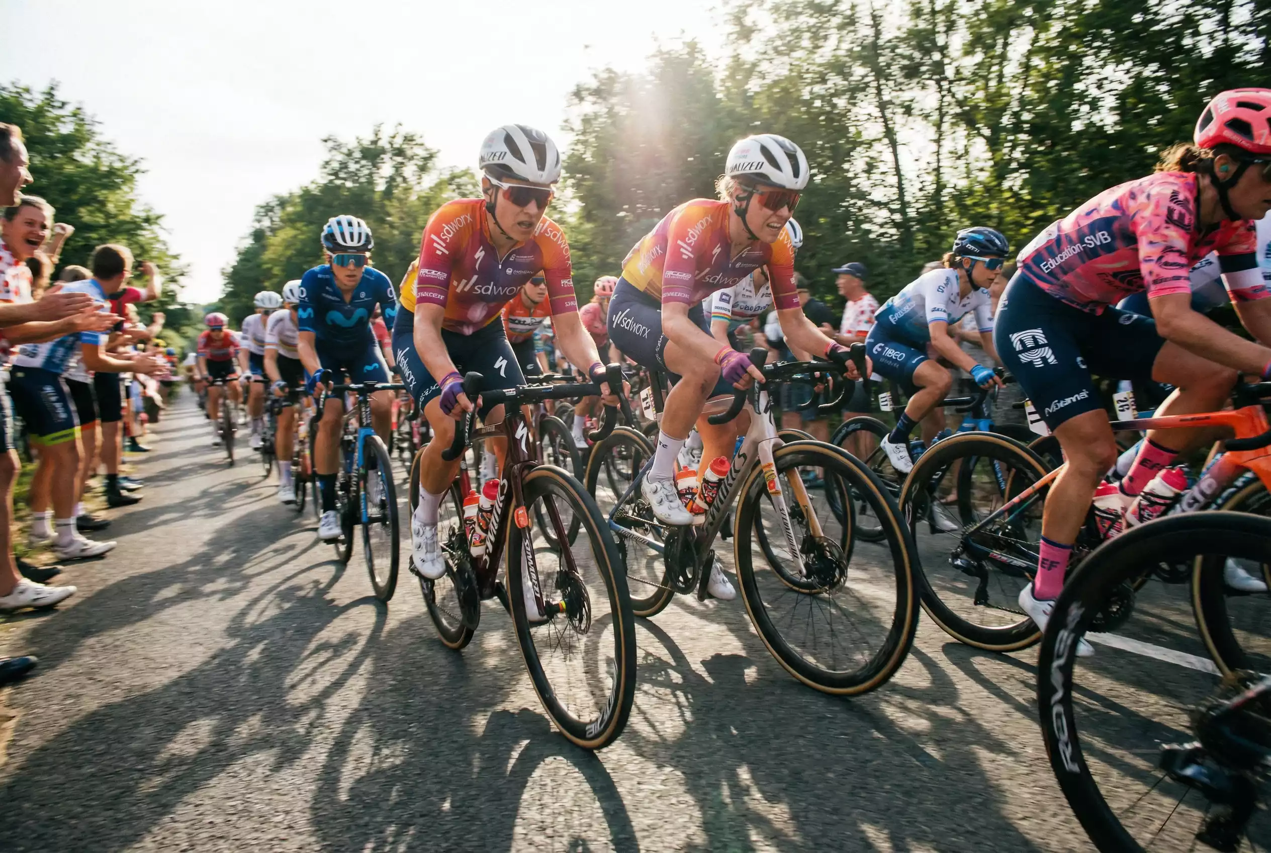 Gruppo di cicliste professioniste in gara su strada asfaltata durante competizione del Women's WorldTour