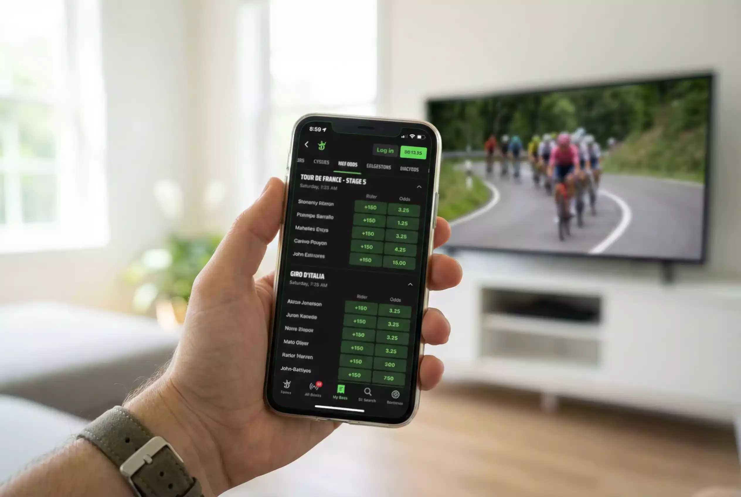 Smartphone con app di scommesse ciclistiche aperta durante una gara di ciclismo