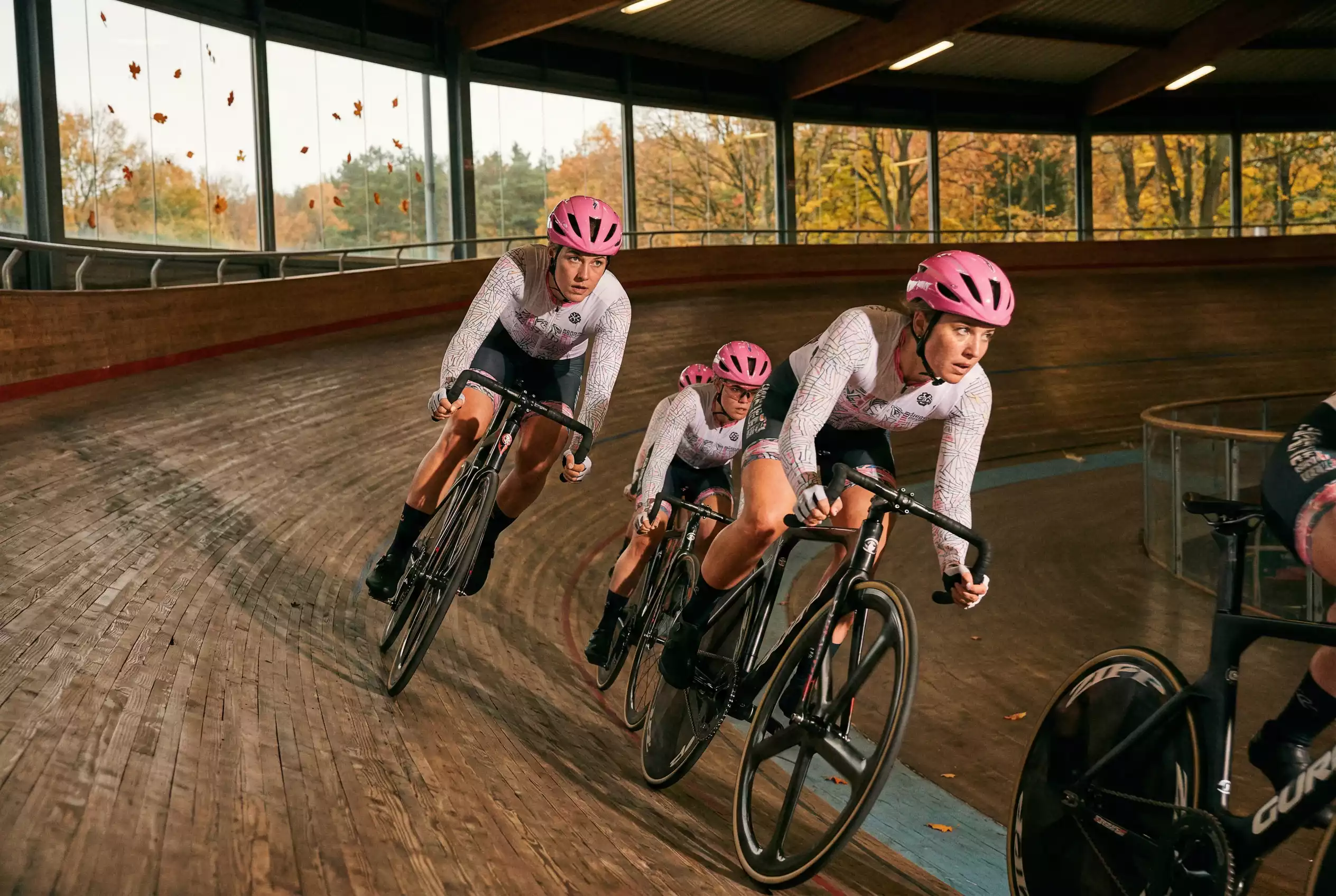Ciclisti su pista in velodromo durante gara di keirin con curve sopraelevate in legno